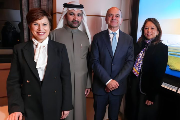 Four professionals in business attire, including a man in traditional Emirati clothing and three individuals in formal suits, standing together in an office setting for a partnership announcement