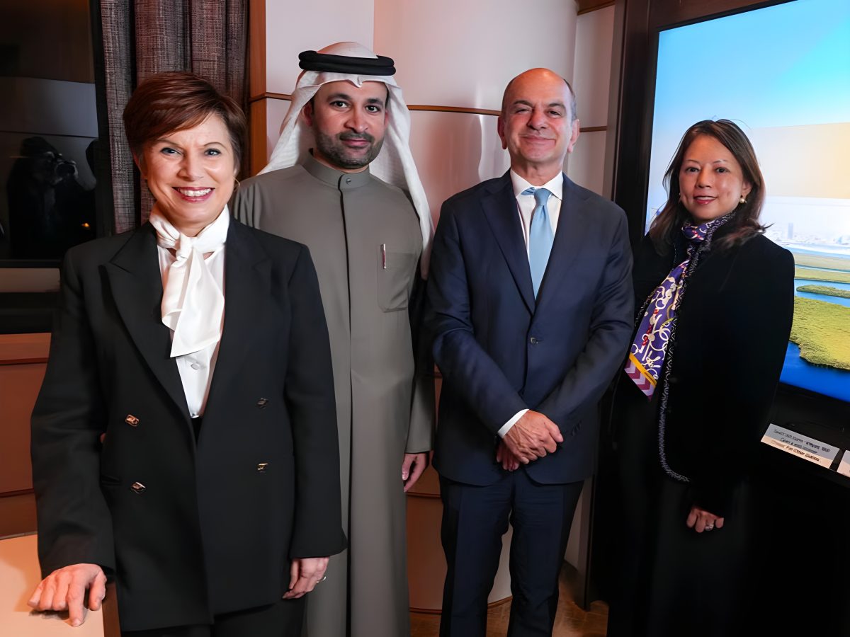 Four professionals in business attire, including a man in traditional Emirati clothing and three individuals in formal suits, standing together in an office setting for a partnership announcement